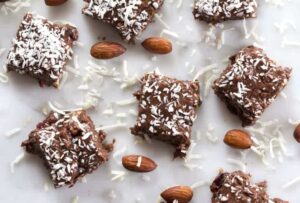 Photo of chocolate almond fudge with almonds and coconut scattered from "Healthy Holiday Treats" by Green Smoothie Girl