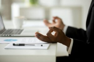 Photo of African American man's hands doing meditation touch at his desk from "11 Natural Ways to Deal with Stress" by Green Smoothie Girl