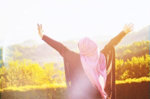 Photo of Muslim woman with veil embracing the sun with big open arms from "11 Natural Ways to Deal with Stress" by Green Smoothie Girl