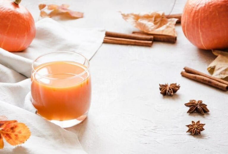 Photo of warm orange drinks in glasses on white tablecloth from "Warm Green Smoothies That Are Perfect For Cold Weather" by Green Smoothie Girl