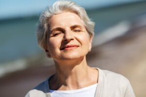 Photo of mature woman smiling with eyes closed towards the sun from "14 Ways I Optimize My Health And Energy Every Day" by Green Smoothie Girl