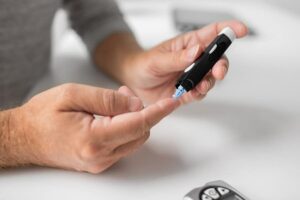 Photo of senior man with glucometer checking blood sugar level at home from "How To Cycle 3-Day Modified Fasts For Healthy, Sustainable Weight Loss" blog post by Green Smoothie Girl