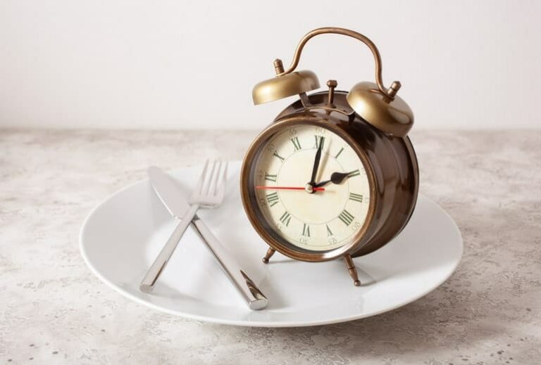 Photo of fork, knife, and alarm clock on empty plate from "How To Cycle 3-Day Modified Fasts For Healthy, Sustainable Weight Loss" blog post by Green Smoothie Girl