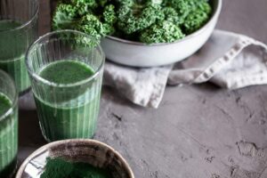 Photo of three green smoothies and two bowls of kale from "9 Green Smoothies For Clear, Younger-Looking Skin From The Inside Out" by Green Smoothie Girl