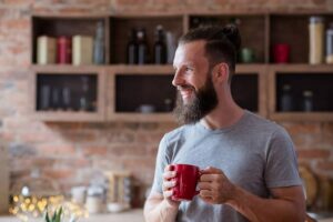 Photo of white man standing in kitchen smiling and holding mug of tea from "How Do I Prepare For a 3-Day Modified Fast?" blog post by Green Smoothie Girl