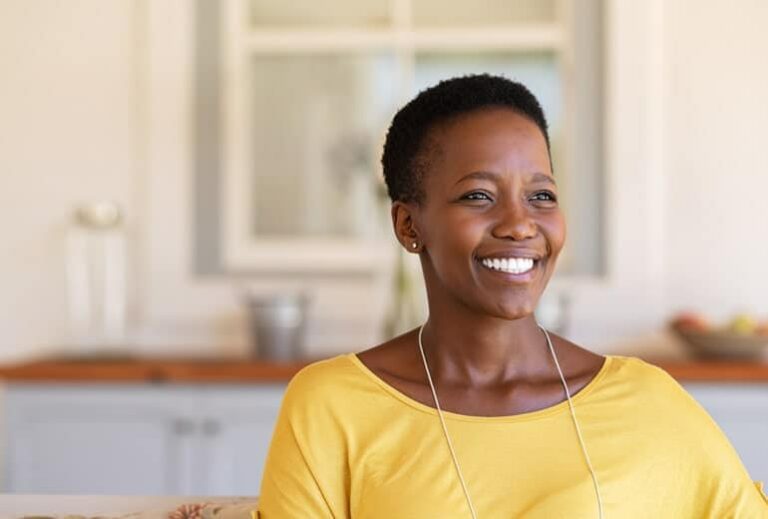 Photo of smiling African American woman in yellow shirt from "9 Green Smoothies For Clear, Younger-Looking Skin From The Inside Out" blog post by Green Smoothie Girl