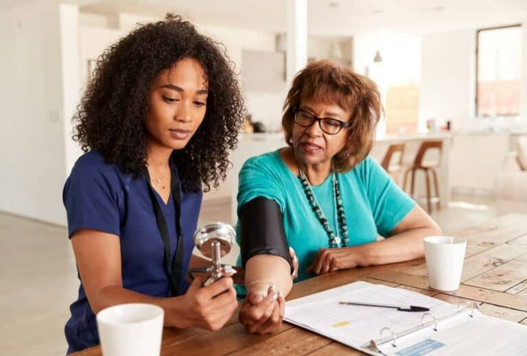 Photo of African American female nurse helping elderly woman take blood pressure from "Can Modified Fasting Help Control Blood Pressure?" by Green Smoothie Girl