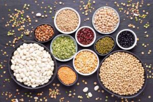 A picture of various legumes in bowls on a black background.