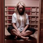 Robyn sitting in a yoga pose in her sauna from Green Smoothie Girl's "19 Benefits of Infrared Saunas"