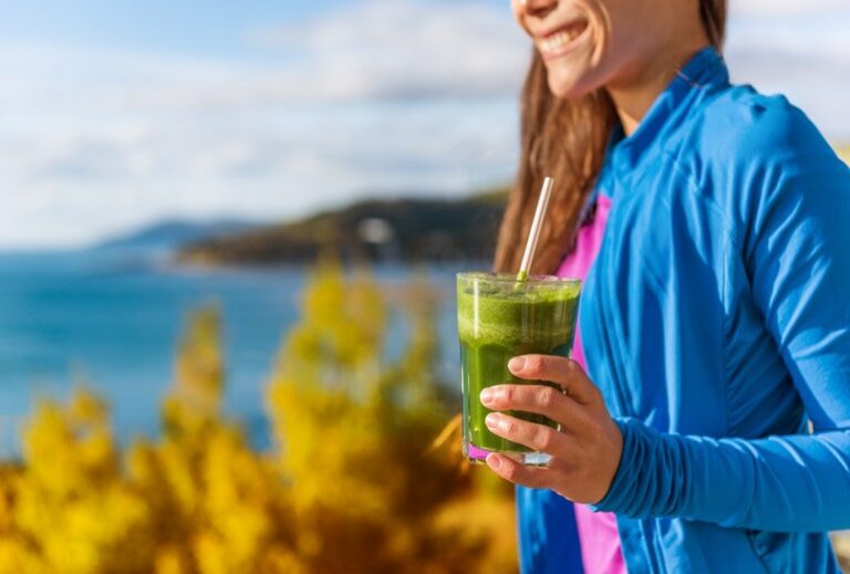 a woman outside holds a green smoothie from Green Smoothie Girl's "10 Fall Smoothies"