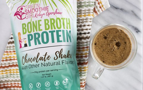 A bag of Green Smoothie GIrl's Bone Broth Protein next to a clear mug of hot chocolate from Green Smoothie Girl's "Easy, Gut-Healthy Bone Broth Hot Chocolate"