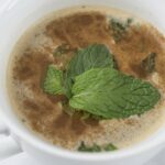 a steaming mug of coffee with mint leaves in it from Green Smoothie Girl's "Healthy High-Protein Peppermint Mocha"