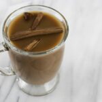 Hot chocolate with cinnamon sticks in a clear mug from Green Smoothie Girl's "Morning Chocolate Elixir"