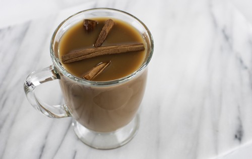 Hot chocolate with cinnamon sticks in a clear mug from Green Smoothie Girl's "Morning Chocolate Elixir"