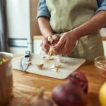 A woman standing in a kitchen cutting an onion from Green Smoothie Girl's "Mmm. Our 10 Favorite Winter Soups Are Warm, Filling, and Delicious!" recipe