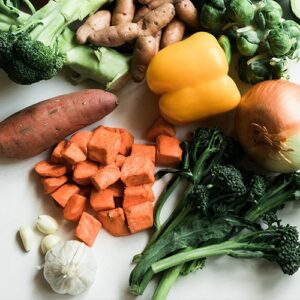 a pile of various veggies: broccoli, sweet potato, garlic, yellow pepper, onion etc.