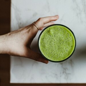 A hand reaching out to a glass of green smoothie