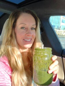 Robyn holding a glass jar of green smoothie