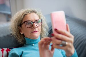 woman wearing blue light glasses while using laptop at night